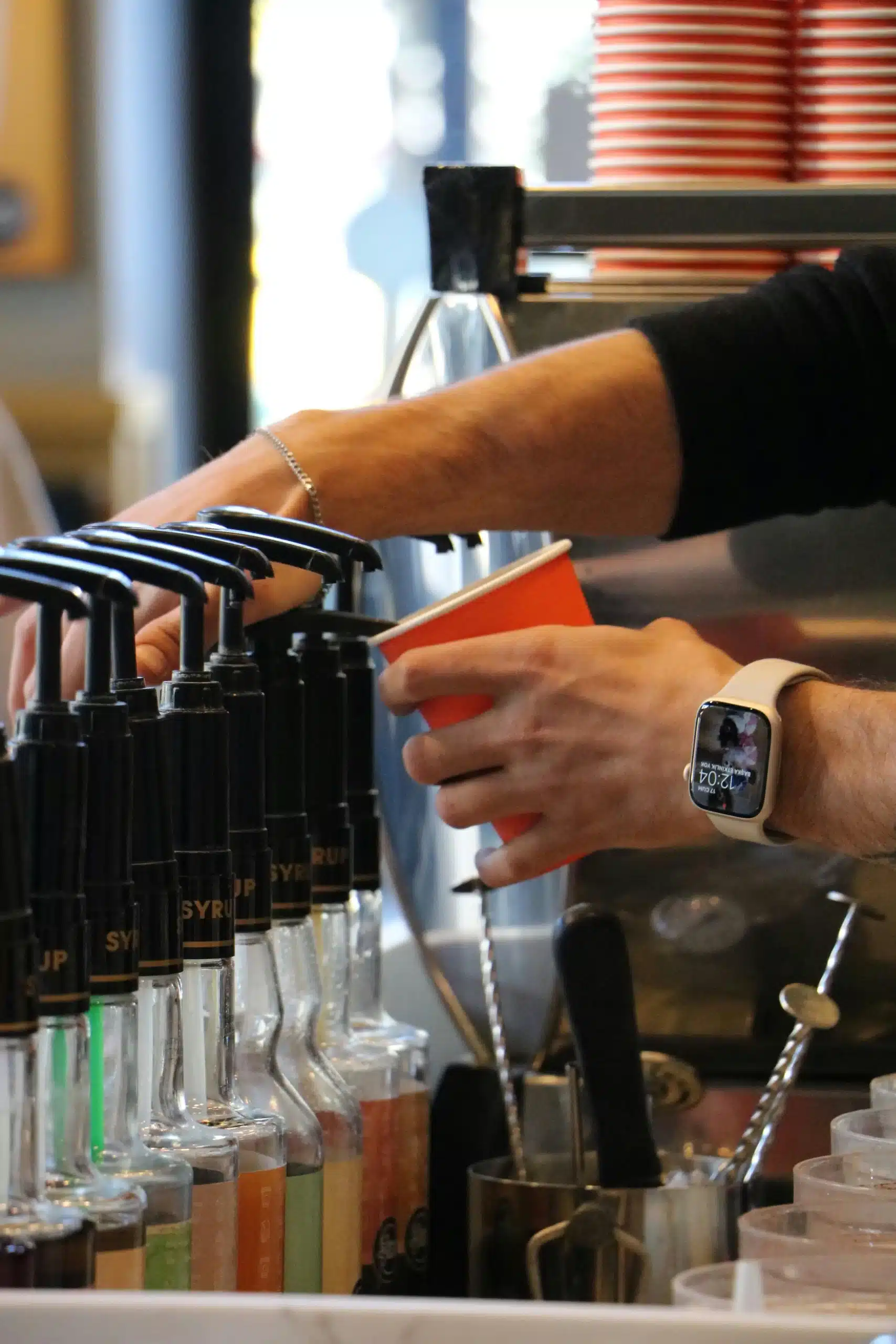A barista pumping syrup into a coffee cup